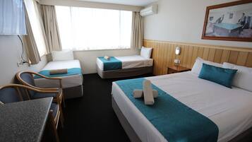 A hotel room with two single beds, a desk, and a chair.