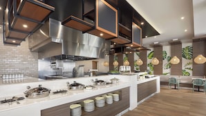 Una cocina moderna con una isla central, electrodomésticos de acero inoxidable y una zona de estar con sofá y sillones.