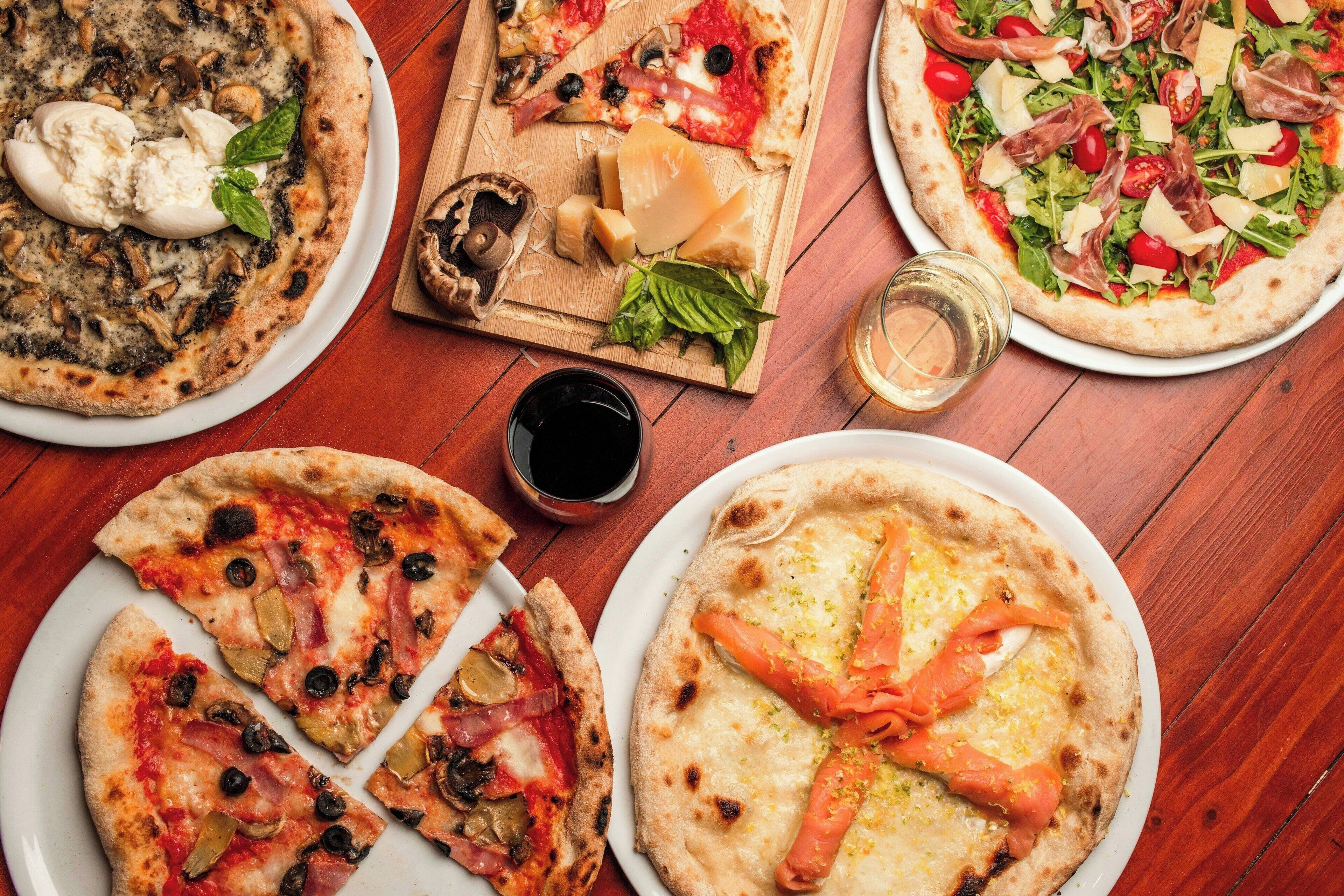 A variety of pizzas on wooden tables.