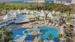 Un resort con varias piscinas, palmeras y arquitectura moderna.