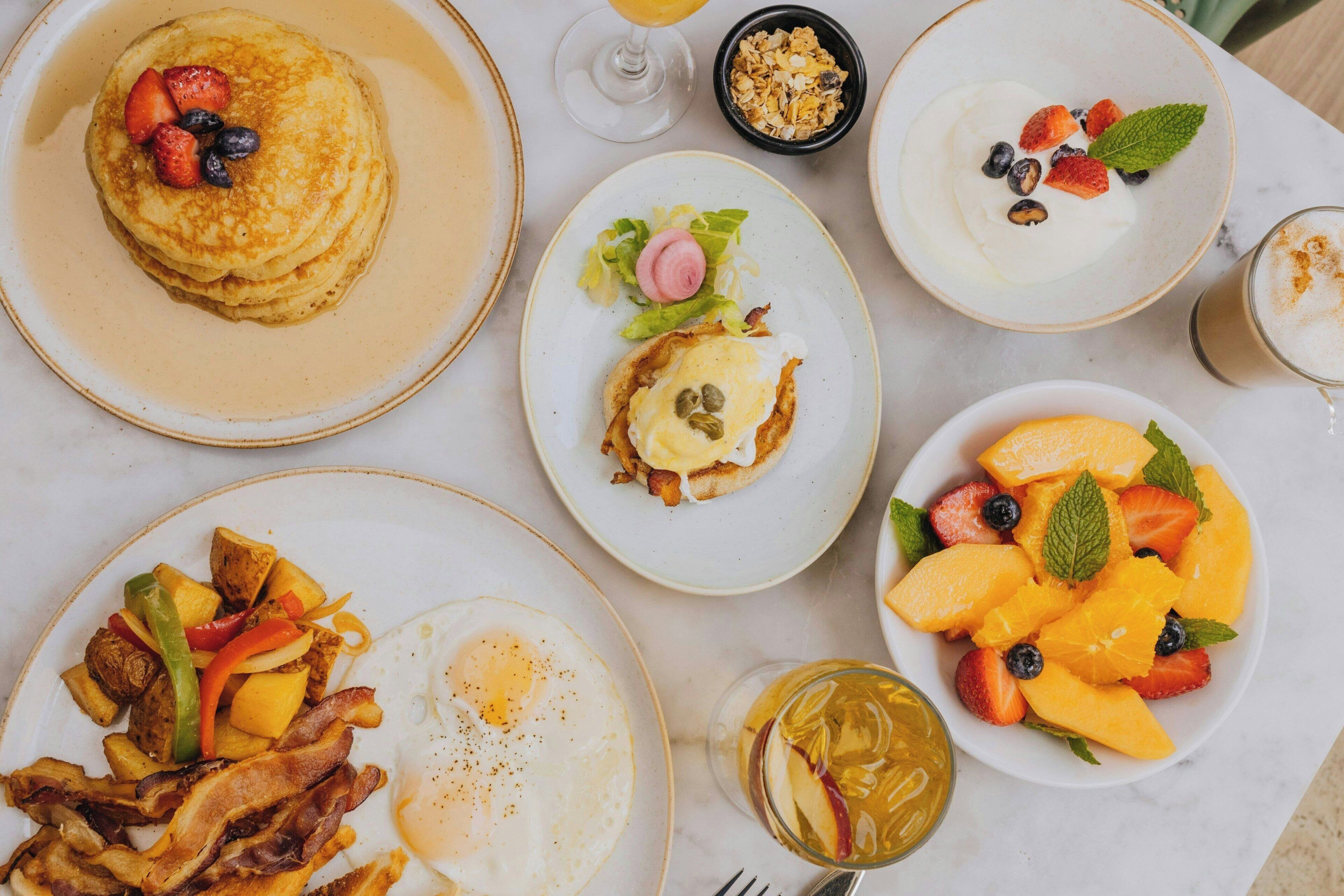 Un petit-déjeuner composé de crêpes, d’œufs, de bacon et de fruits.
