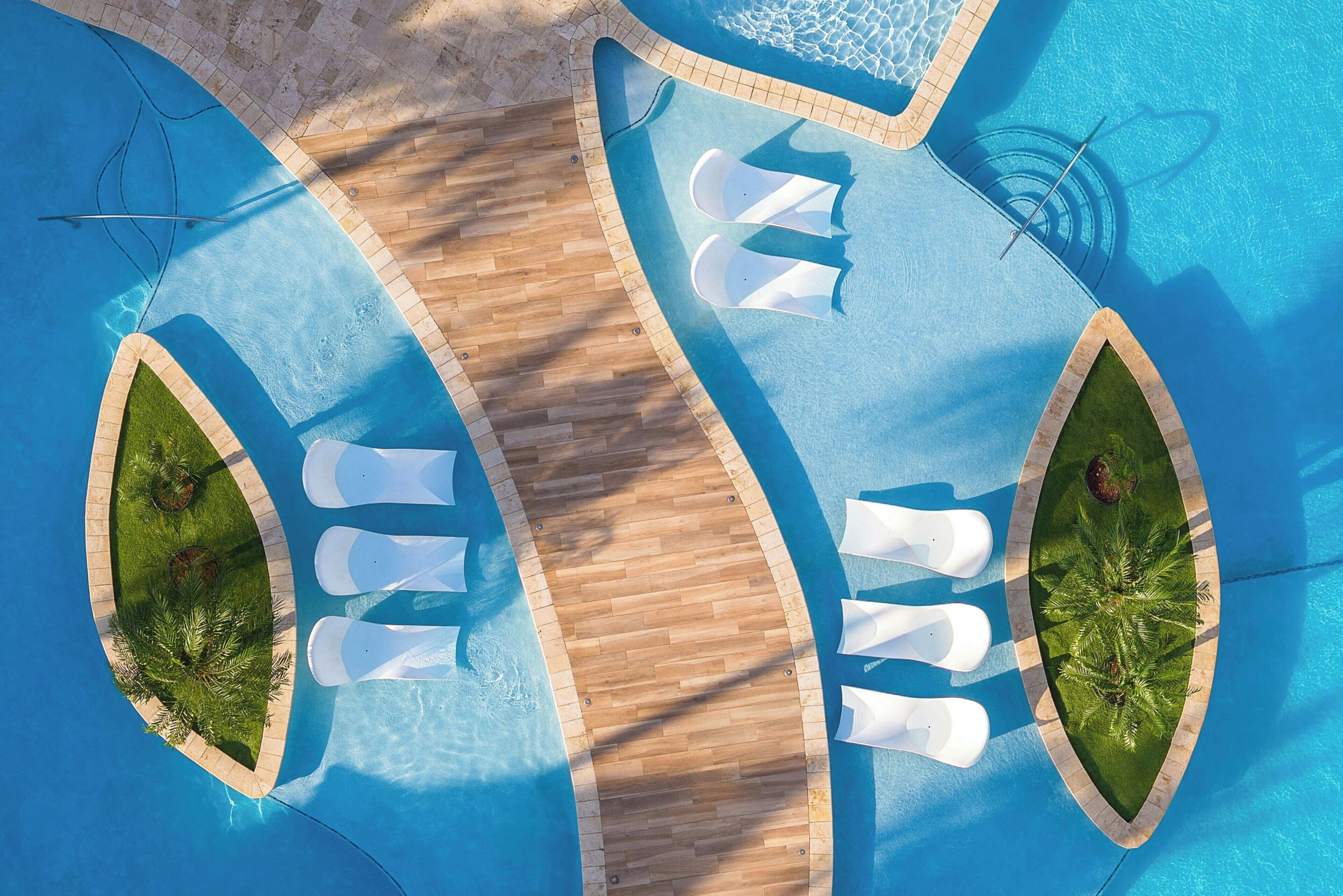 An aerial view of a swimming pool with two sun loungers and a wooden deck.