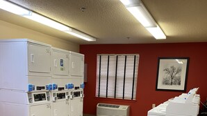 A laundry room with stacked washers and dryers, a vent, and a framed picture on the wall.