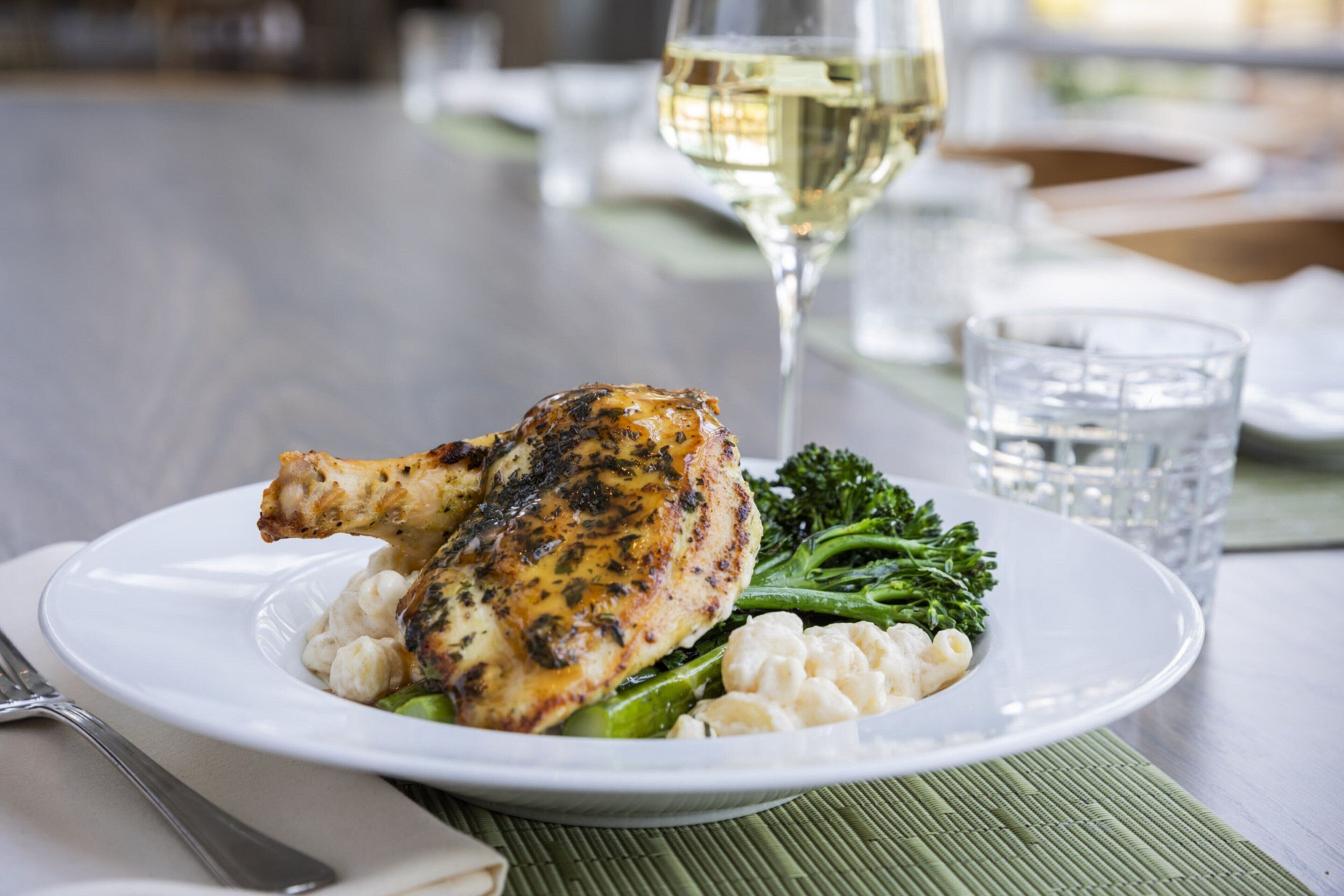 Un plato de comida con una copa de vino blanco sobre una mesa.