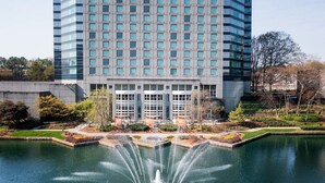 A modern hotel with a large water fountain in the courtyard, surrounded by greenery and a reflective pool. - The Westin Atlanta Perimeter North (Atlanta)