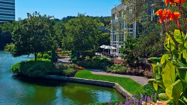 A landscaped garden with a pond, seating areas, and a building in the background. - The Westin Atlanta Perimeter North (Atlanta)