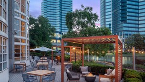 An outdoor patio with tables and chairs, a wooden pergola, and a fire pit. - The Westin Atlanta Perimeter North (Atlanta)