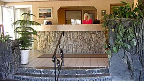 A reception area with a receptionist, a stone wall, and a staircase leading to the upper floor.