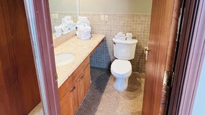 A bathroom with a wooden vanity, a toilet, and a sink.