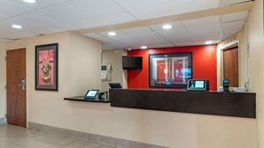 Zona de recepción con mostrador, televisor y quiosco digital.