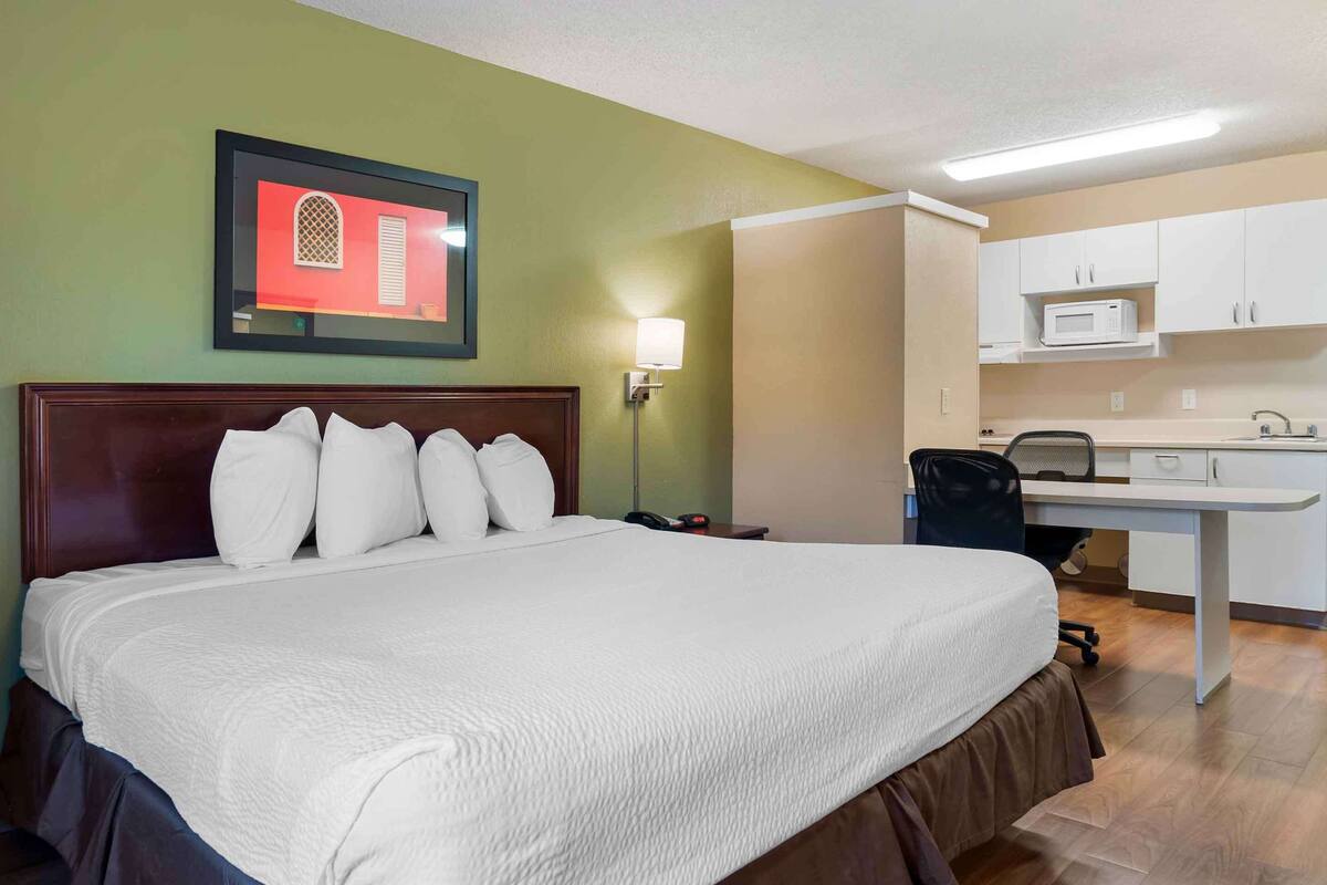 Habitación de hotel con una cama grande, un escritorio y una kitchenette.