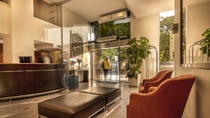Un vestíbulo moderno con mostrador de recepción, zona de estar y ventanas amplias.