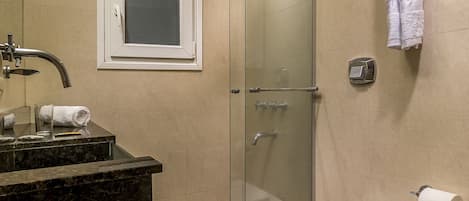 Un baño moderno con cabina de ducha de vidrio, inodoro, lavamanos y toallero.