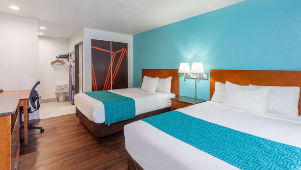 A hotel room with two beds, a desk, and a chair. - Howard Johnson by Wyndham National City/San Diego South (National City)