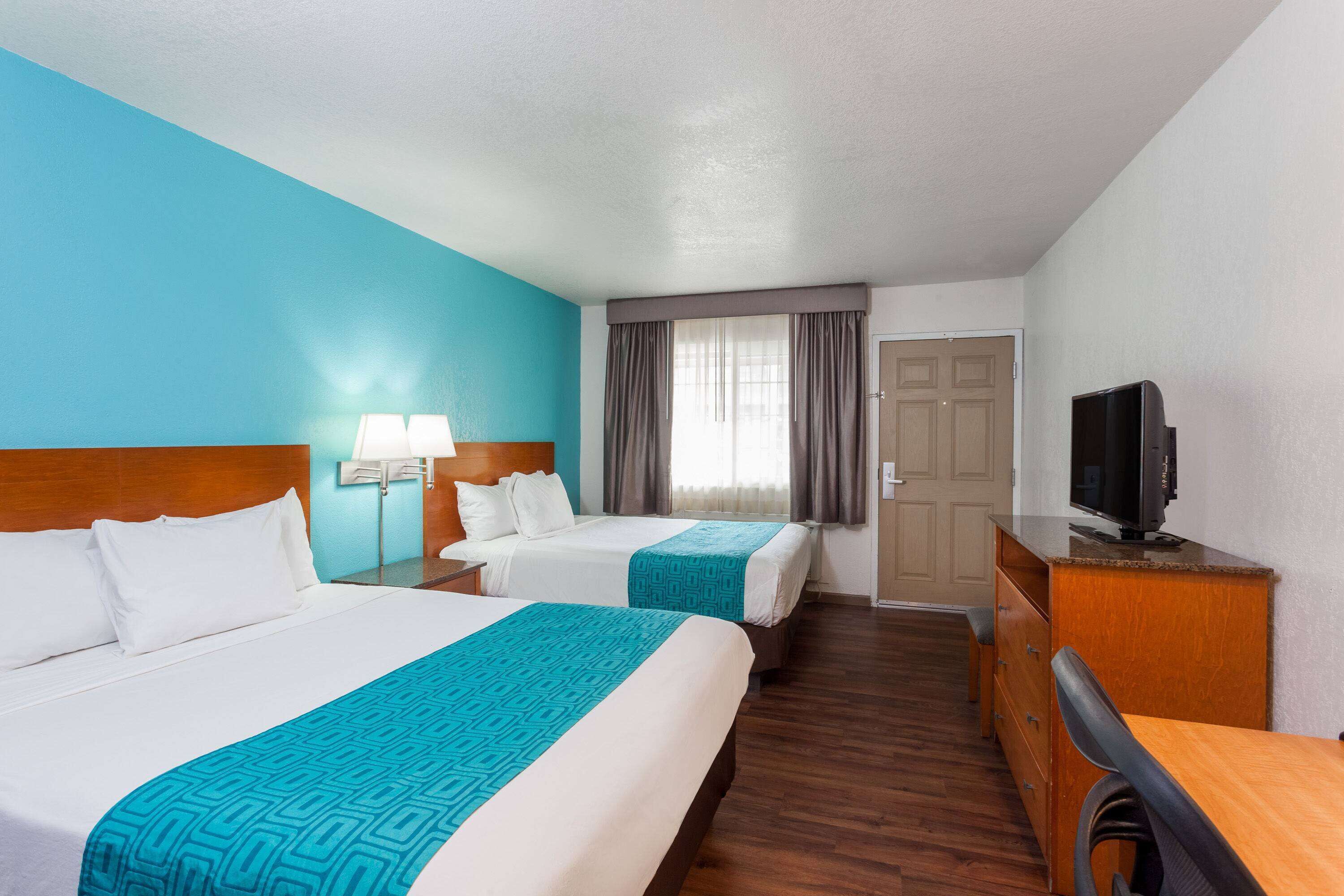 Une chambre d’hôtel avec deux lits, une télévision, un bureau et une commode.