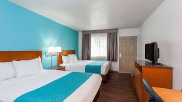 Une chambre d’hôtel avec deux lits, une télévision, un bureau et une commode.