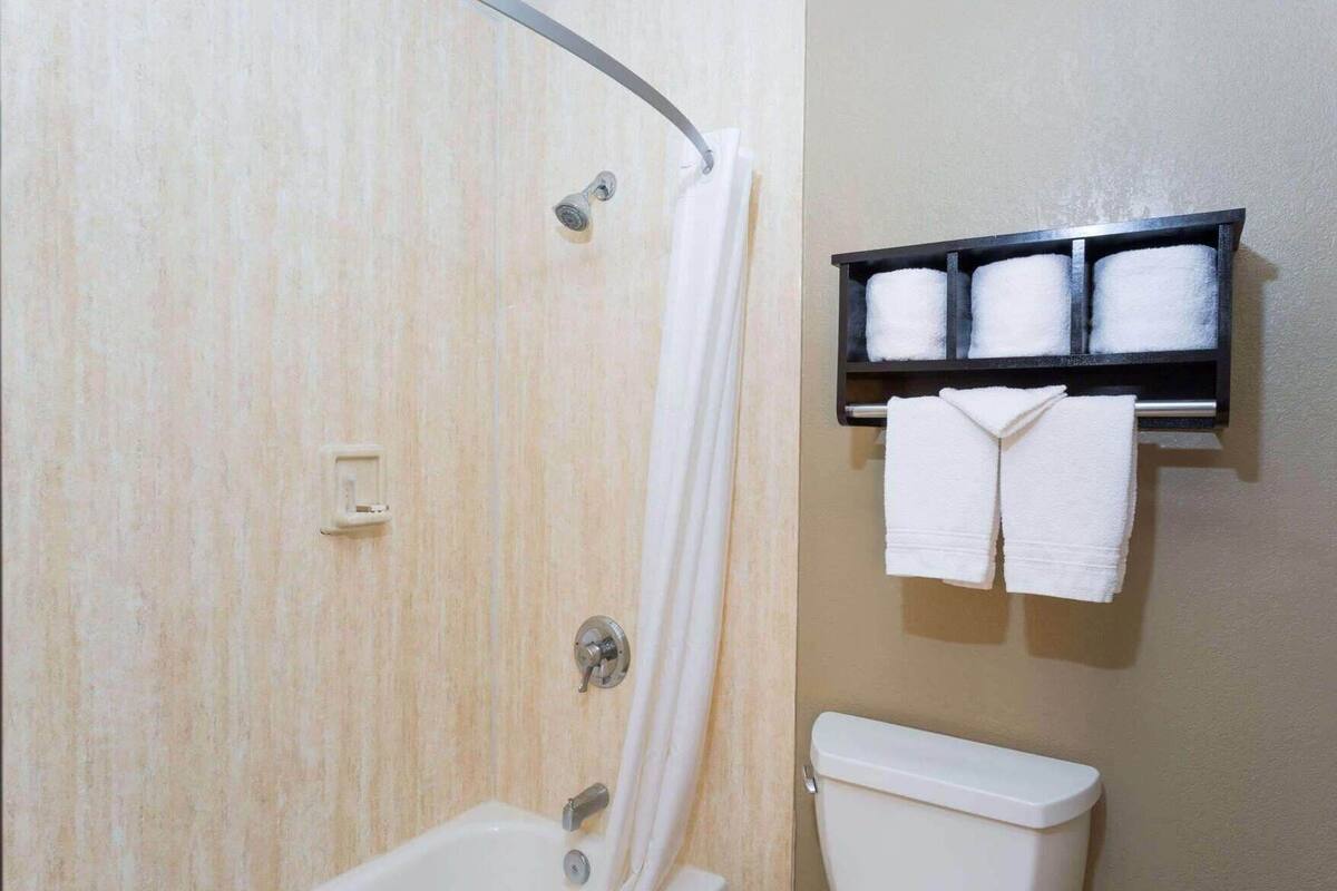 A bathroom with a shower, toilet, and a towel rack with towels.