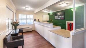 A reception area with a green wall, a reception desk, a phone, a window, and a chair.