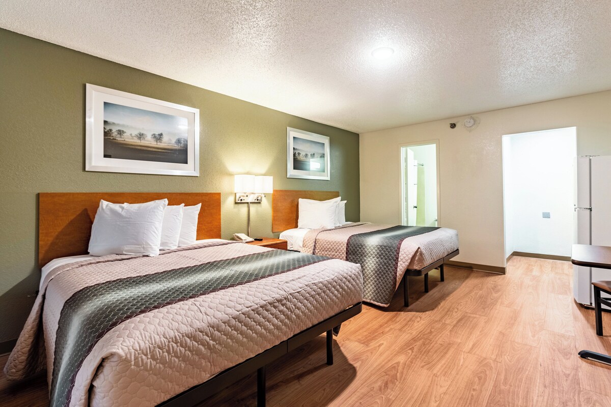 Habitación de hotel con dos camas, un escritorio y una silla.