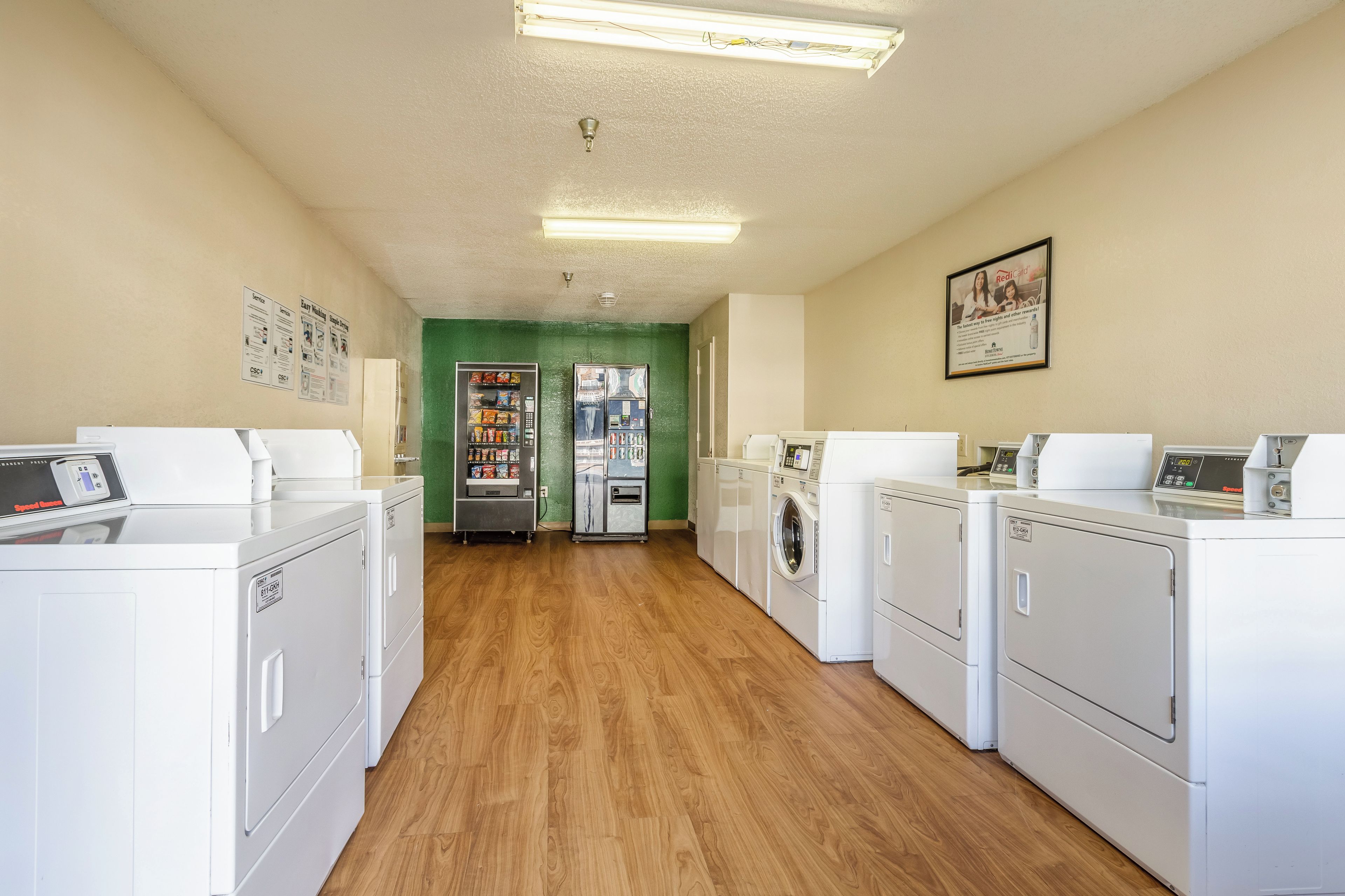 A laundry room with multiple washing machines, dryers, and a vending machine.