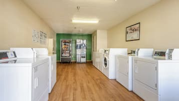 A laundry room with multiple washing machines, dryers, and a vending machine.