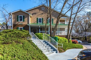 A two-story building with a green roof, a front porch, and a staircase leading to the entrance. - HomeTowne Studios by Red Roof Atlanta - Norcross Downtown (Norcross)