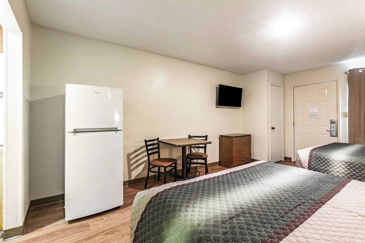 A hotel room with a bed, a desk, a chair, a television, and a wardrobe.