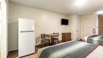 Quarto de hotel com cama, escrivaninha, cadeira, televisão e armário.
