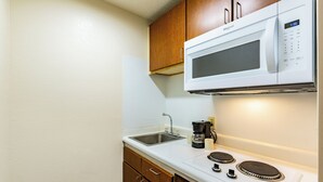 A compact kitchenette with a microwave, a coffee maker, and a stove.