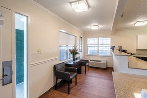 A modern interior with a seating area, a kitchen counter, and a large window providing natural light. - HomeTowne Studios by Red Roof Atlanta - Norcross Downtown (Norcross)