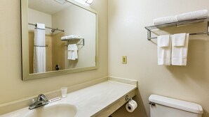 A bathroom with a sink, mirror, toilet, and towel rack. - HomeTowne Studios by Red Roof Atlanta - Norcross Downtown (Norcross)