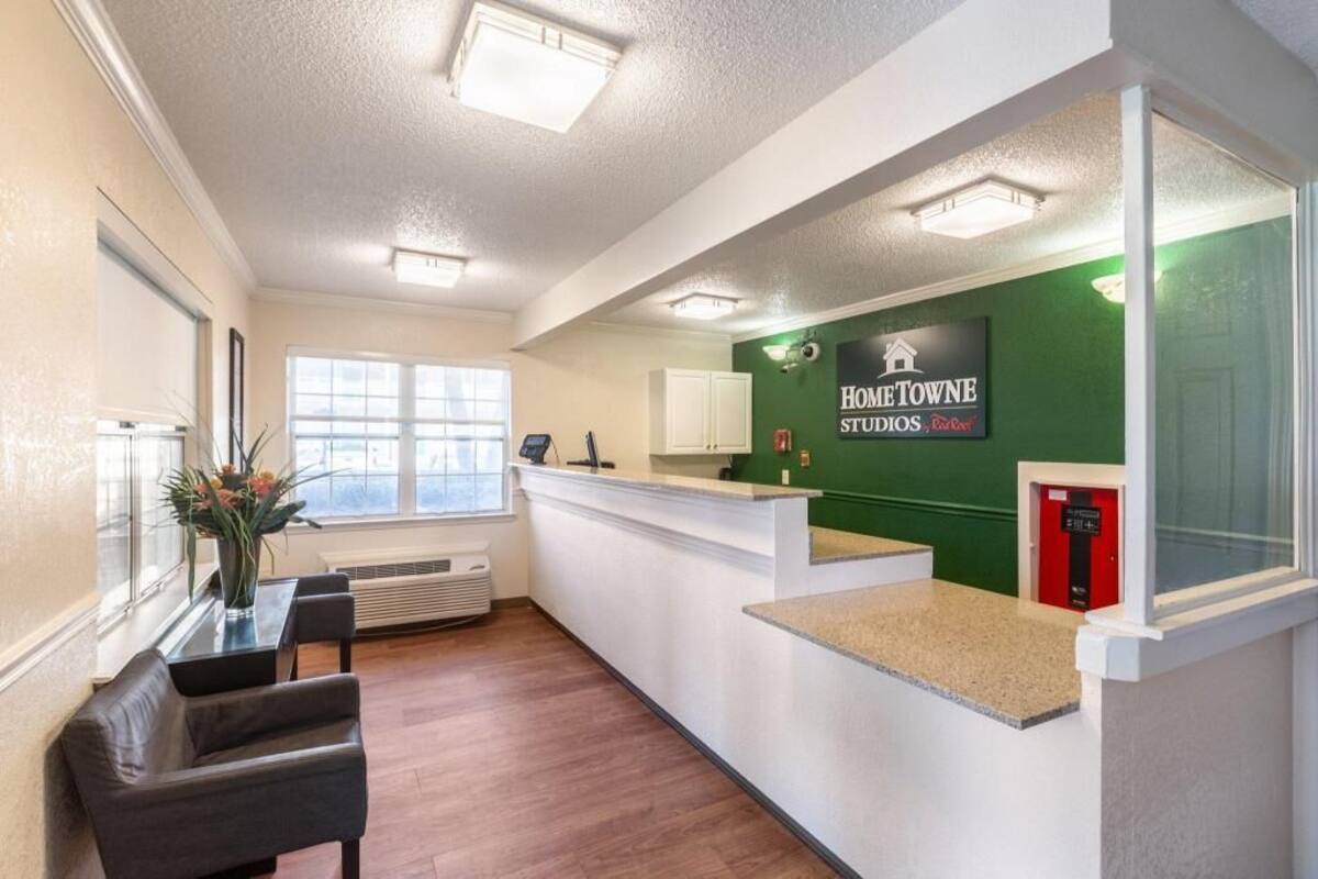 A reception area with a counter, a desk, chairs, a window, and a green wall with a sign.