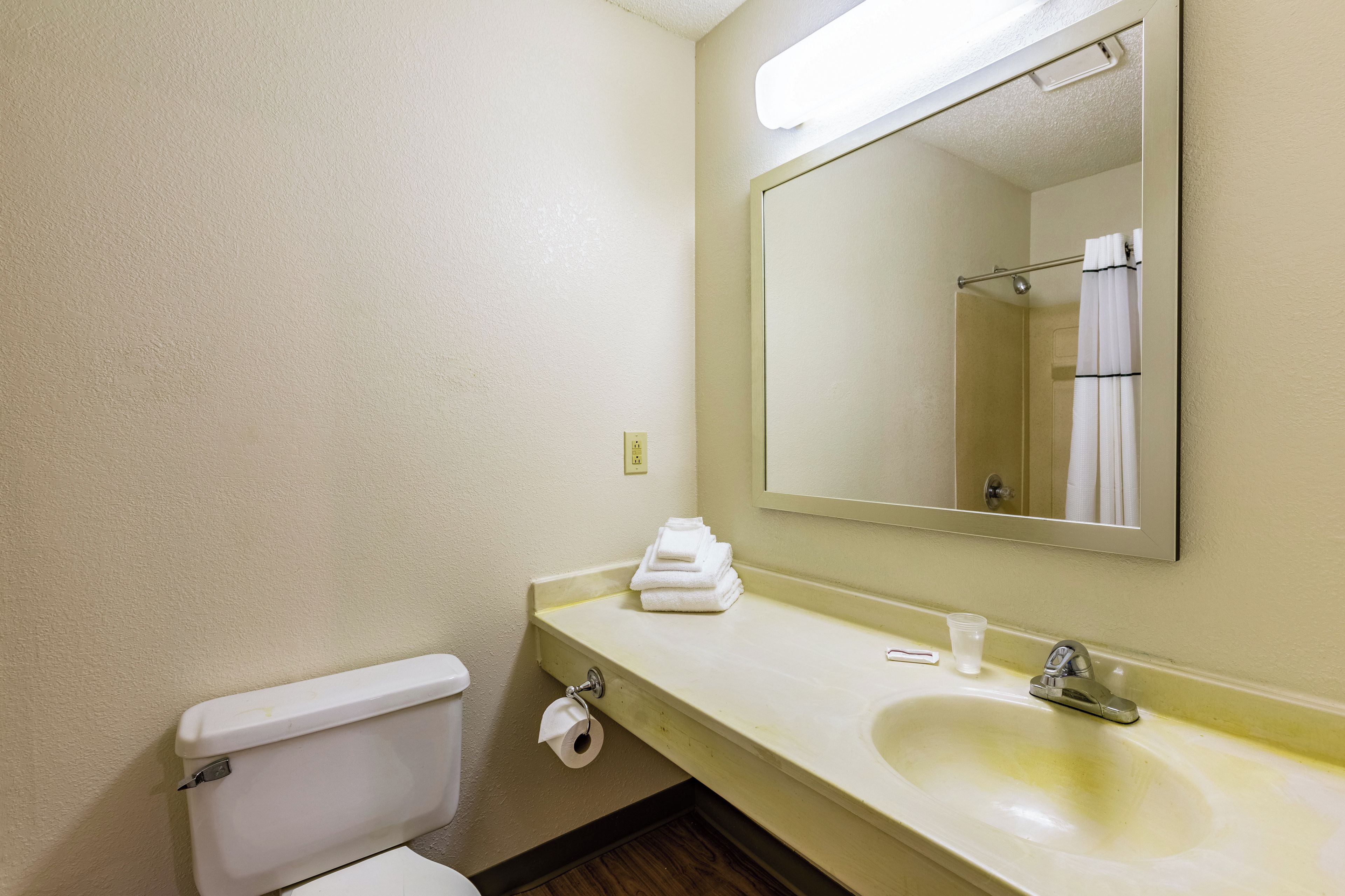 A bathroom with a toilet, sink, and mirror.