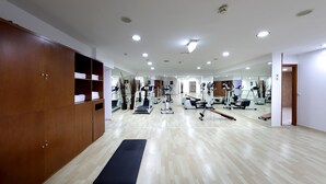Un gimnasio con armarios de madera, una colchoneta de ejercicio negra y diversos equipos de entrenamiento.