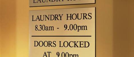 Señal con el horario de la sala de lavandería e indicando que las puertas se cierran a las 21:00.