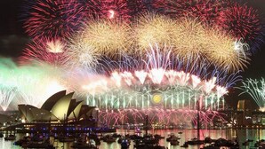 Une vue nocturne de l’Opéra de Sydney, avec des feux d’artifice en arrière-plan.