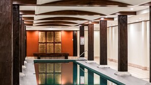 A hotel corridor with a pool, wooden columns, and a seating area with bags of coffee. - Oaks Sydney Goldsbrough Suites (Pyrmont)