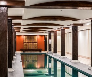 A hotel corridor with a pool, wooden columns, and a seating area with bags of coffee. - Oaks Sydney Goldsbrough Suites (Pyrmont)