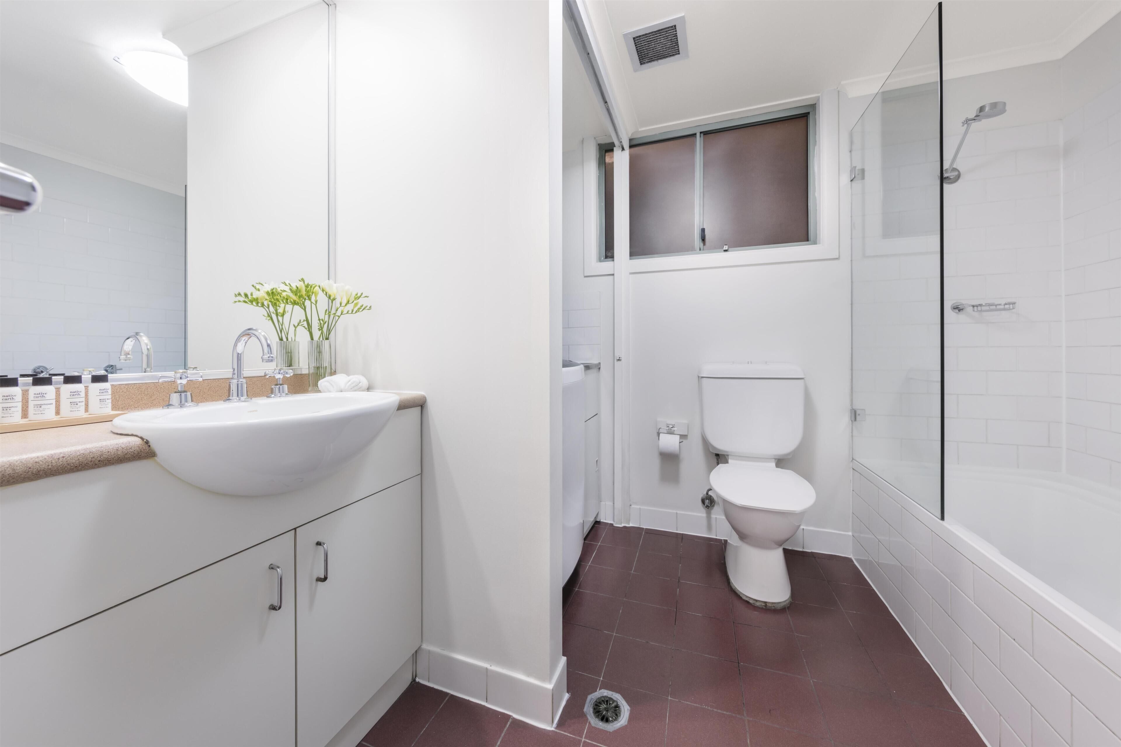 Een moderne badkamer met een witte wastafel, toilet en douche.