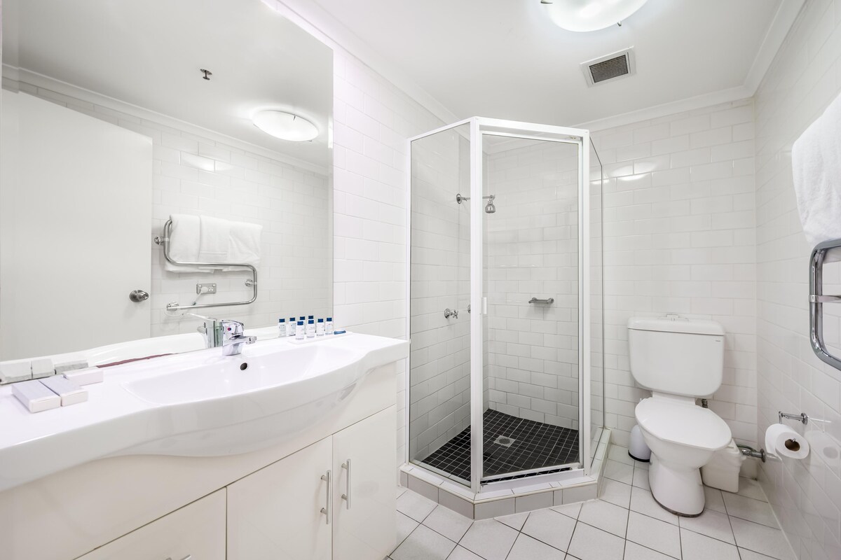 A modern bathroom with a white sink, mirror, and toilet.