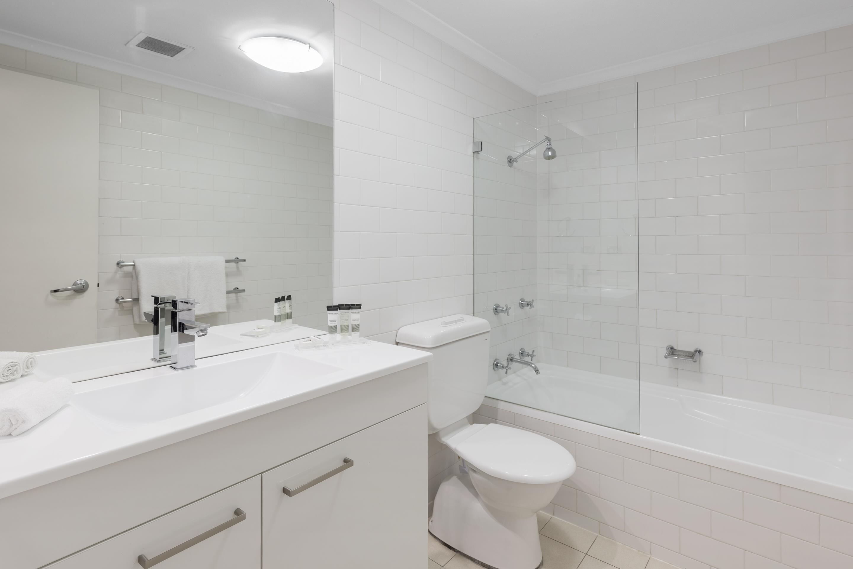 A modern bathroom with a white sink, mirror, and toilet.