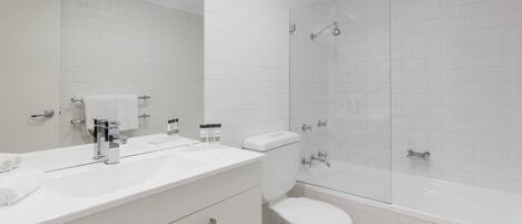 A modern bathroom with a white sink, mirror, and toilet.
