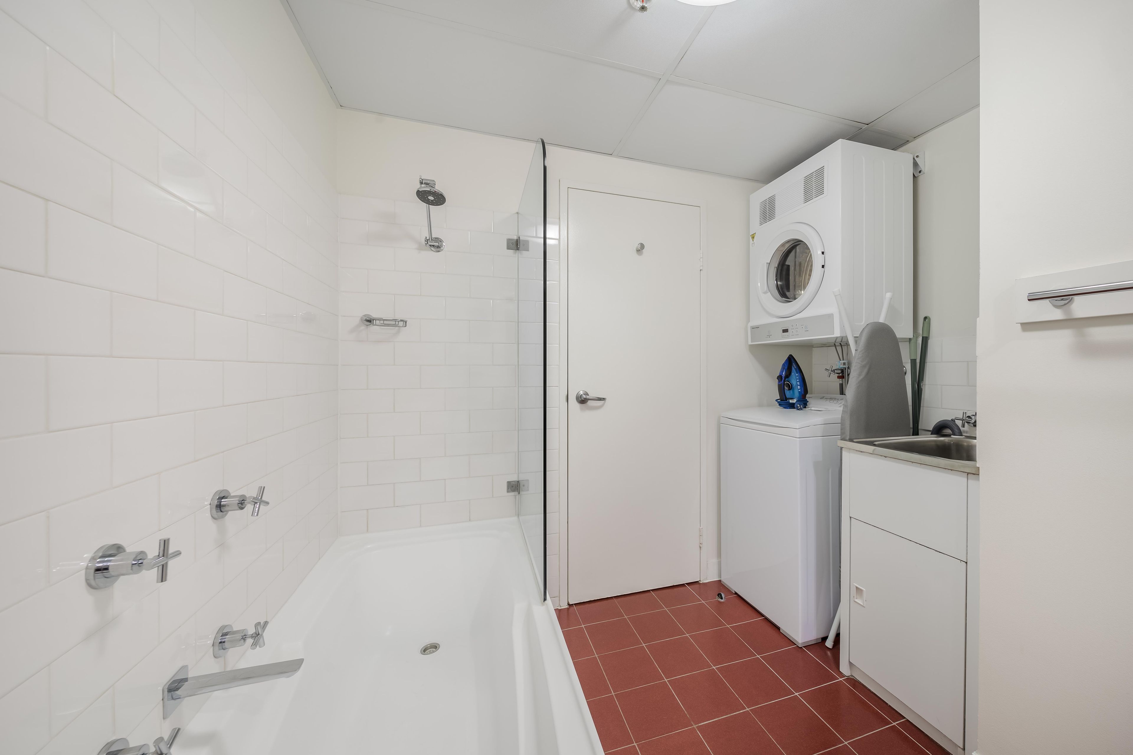 A bathroom with a bathtub, a shower, and a built-in washing machine.