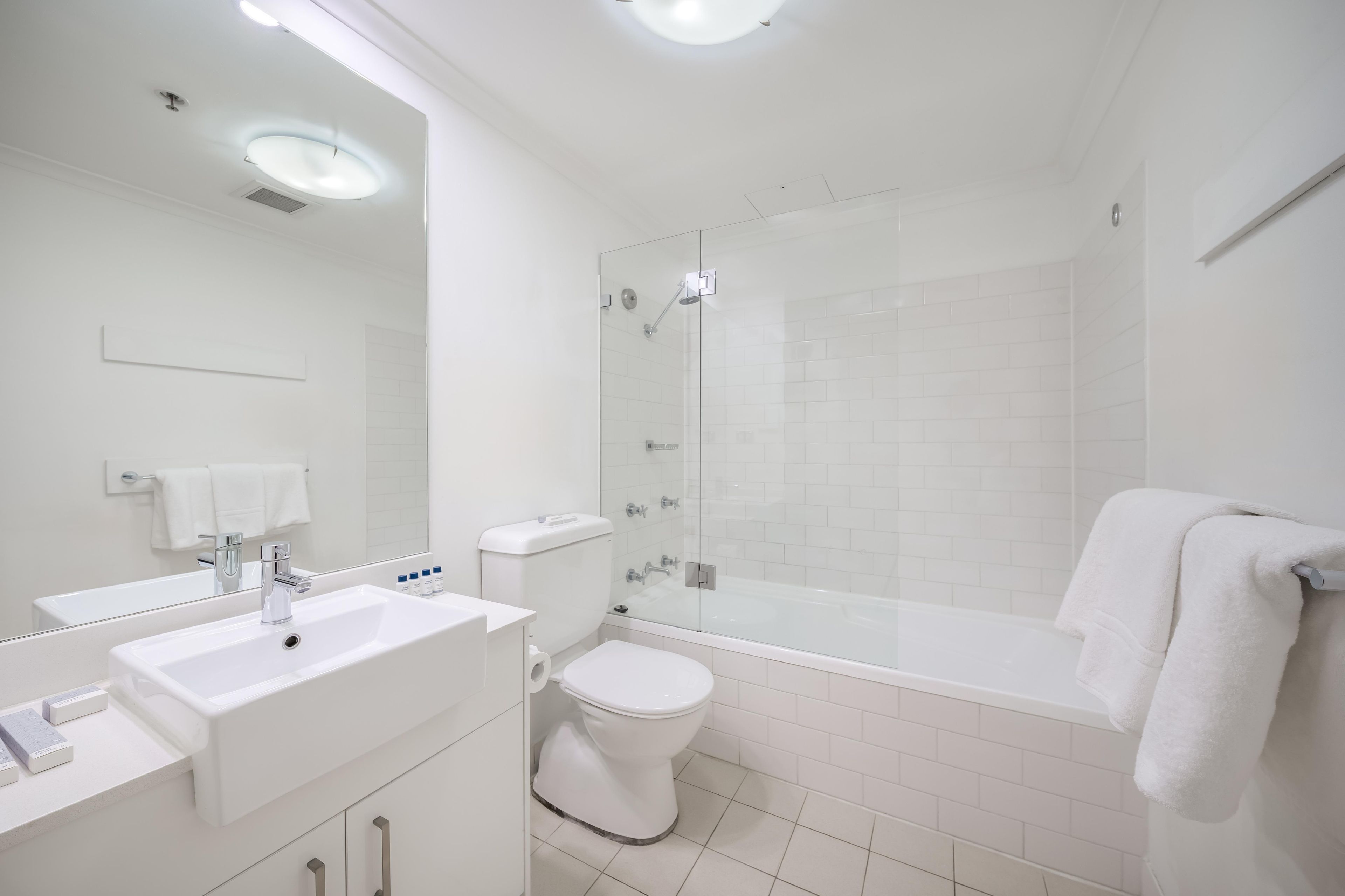 A modern bathroom with a glass-enclosed shower, a white sink, and a toilet.