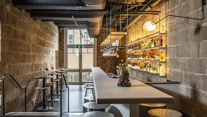 Uma área de bar moderna com um balcão comprido, banquetes e uma parede de tijolos.
