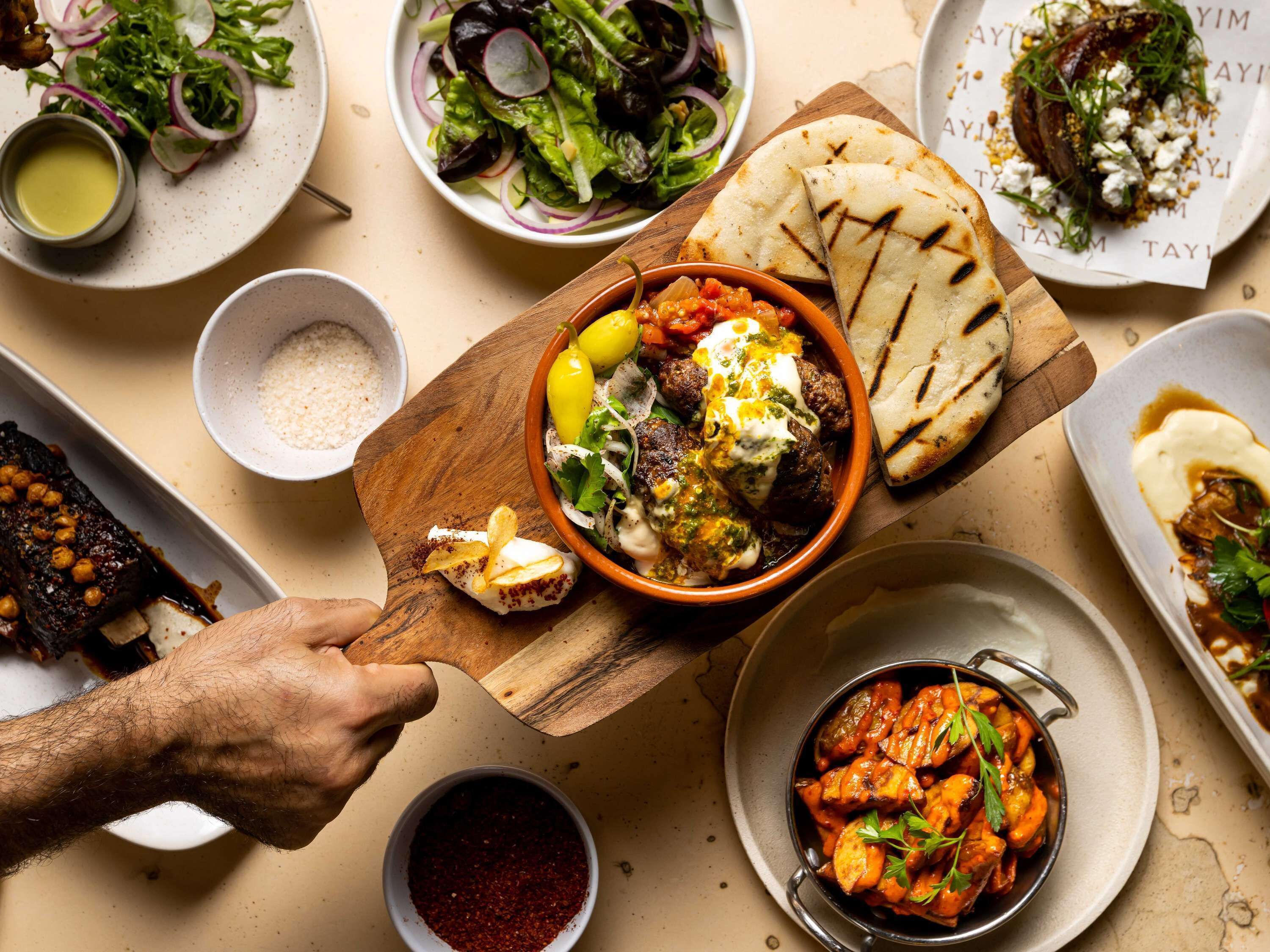 A variety of dishes including a bowl of meatballs with sauce, a plate of flatbread, and a bowl of roasted vegetables.
