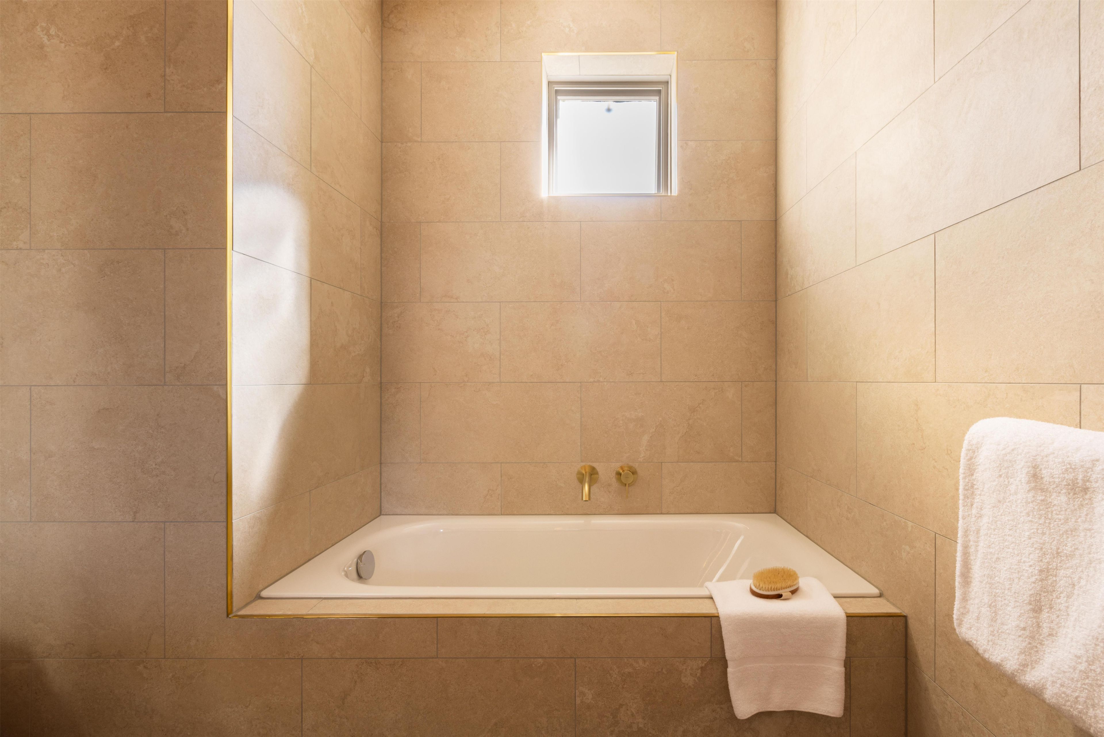 A bathroom with a bathtub, a window, and a towel rack.