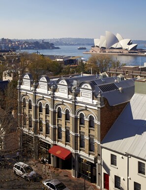 A hotel with a red awning, labeled 'Harbour Rocks Hotel', featuring a classic architectural style with arched windows and a brick facade.