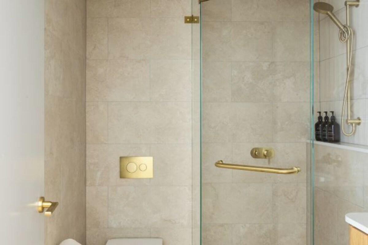 Un baño moderno con cabina de ducha de vidrio, inodoro y barandilla.