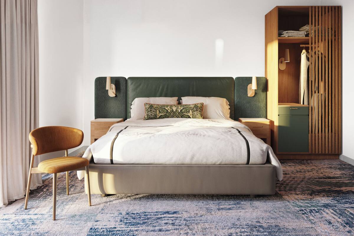 A bedroom with a bed, a chair, a wardrobe, and a nightstand.